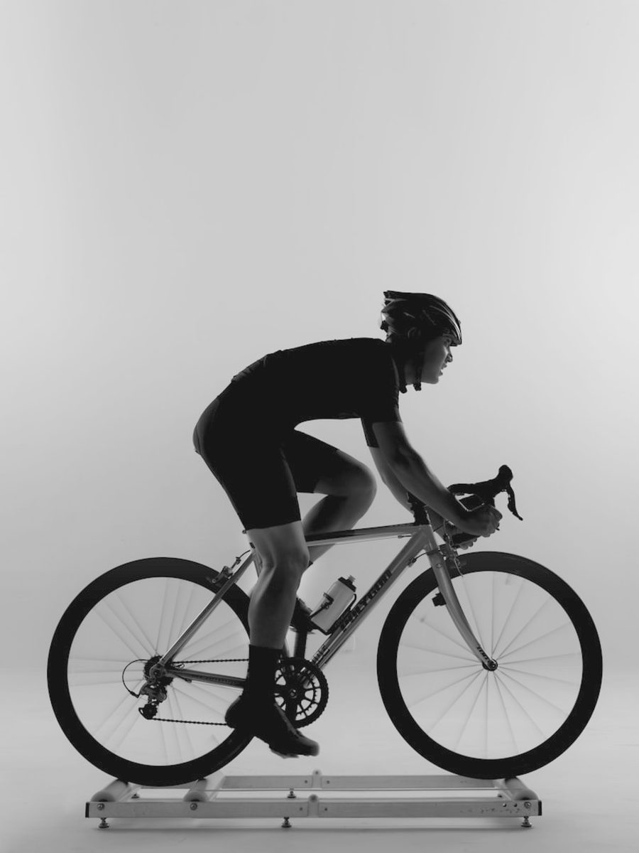 A rider on a road bike set up on an indoor trainer, photographed side on
